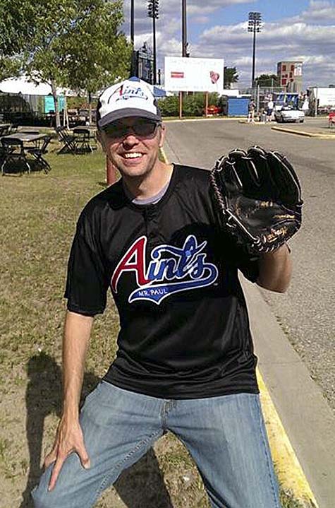 Photo of Eric in Aints t-shirt and cap, wearing a baseball glove.