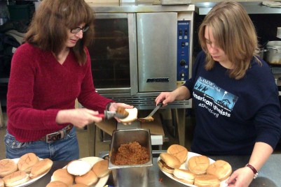 Photo of two volunteers working in a commercial kitchen.