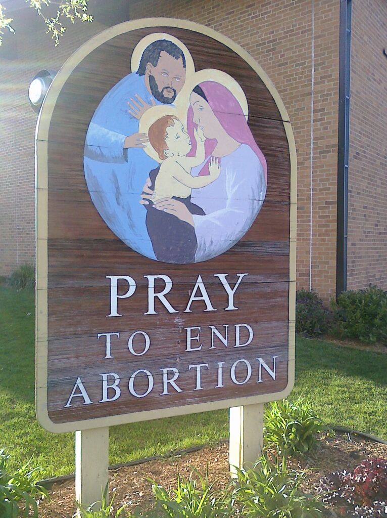 Photo of sign featuring Jesus, Mary, and Joseph and the text "Pray to end abortion".